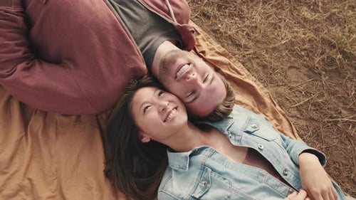 Close-up of young couple lying on blanket in the park from outside