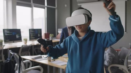 Young Boy in AR Headset, with Controllers Testing his Project at Coding School