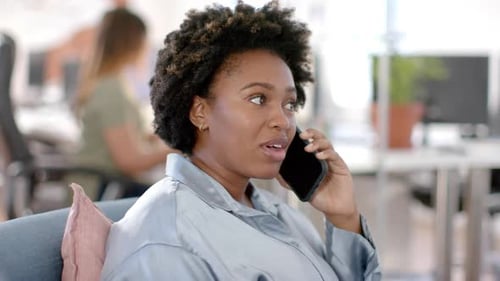 Happy african american casual businesswoman talking on smartphone in office, slow motion