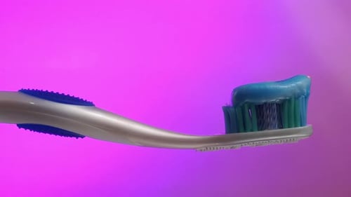Toothbrush with Blue Toothpaste on Pink Background for Oral Care Focus