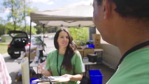 Volunteers With Clipboard Talking In Sunny Parking Lot
