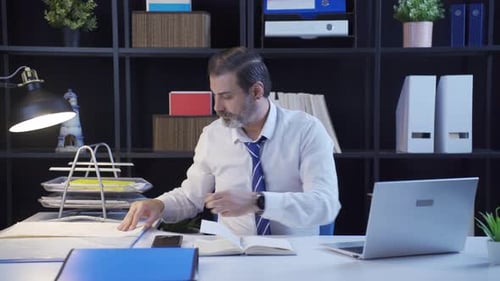 Businessman reviewing projects, working in dark space.