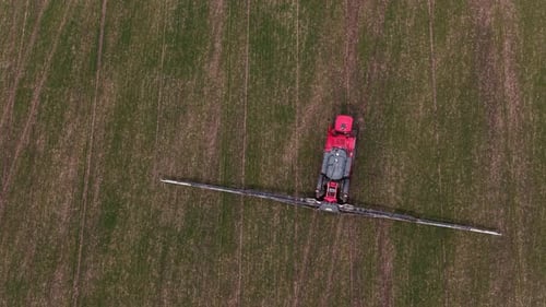 Aerial drone view of agricultural machinery spraying the field and working the land