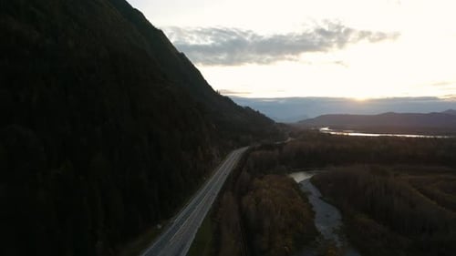Route panoramique dans une vallée au bord de la rivière entourée de montagnes, coucher de soleil, saison automnale, paysage aérien