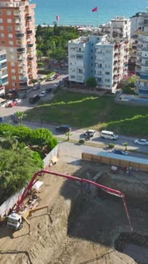 Vídeo vertical: equipo pesado y trabajadores que colaboran en una obra