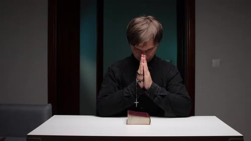 Young Adult Praying with Rosary Indoors