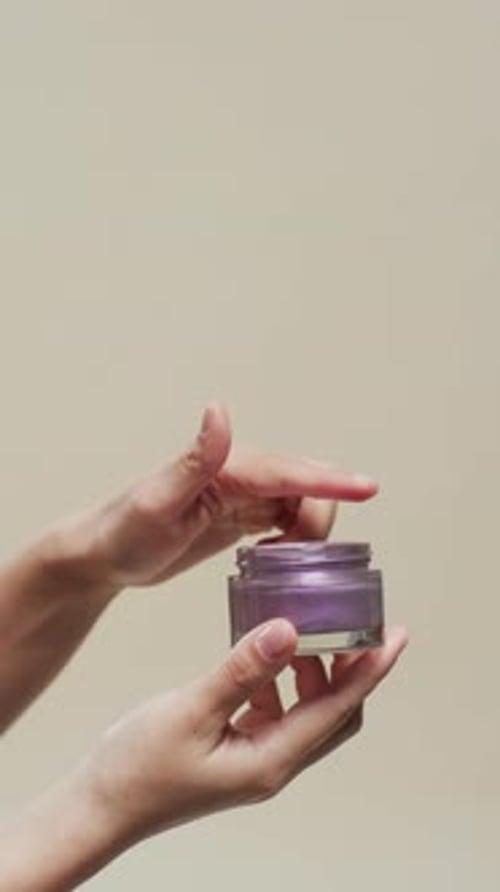 Hands Display Purple Moisturizing Cream in Vertical Format
