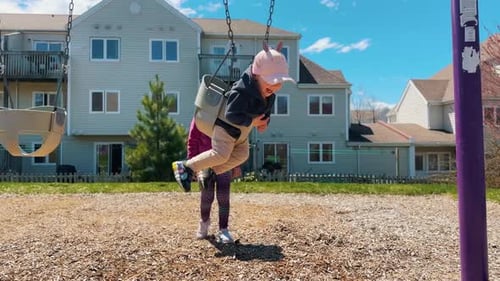 Children Ride on a Swing in the Playground in the Park
