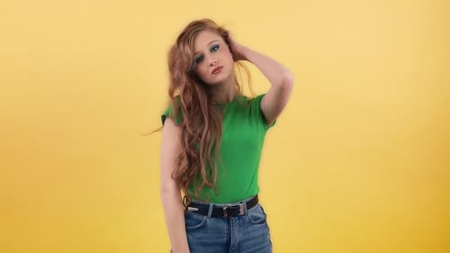 A Young Woman in a Green Tshirt Poses for the Camera on an Orange Background Pleasant Redhaired
