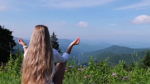 Woman Meditating Peacefully in Stunning Mountain Landscape Under Blue Sky