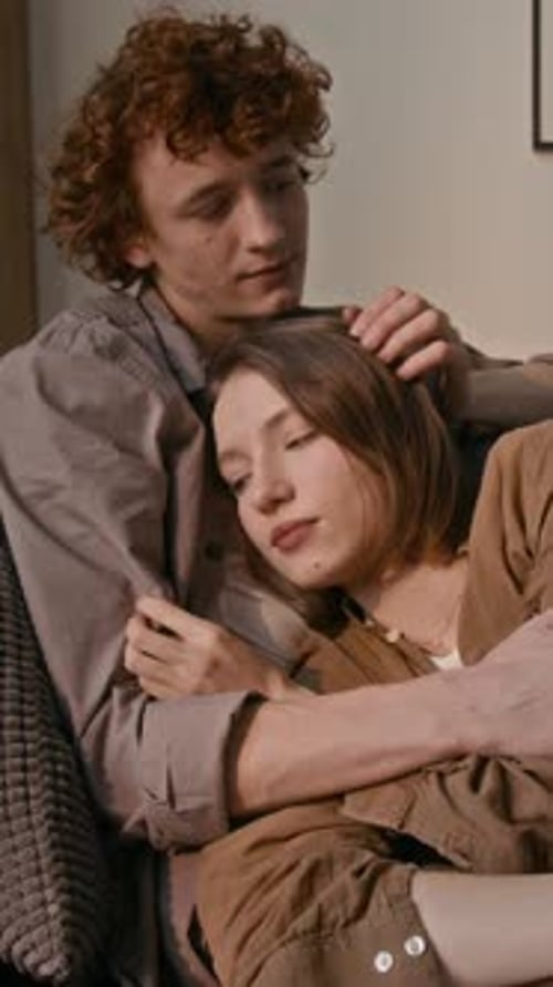 Joven sosteniendo a su novia en sus brazos en el sofá