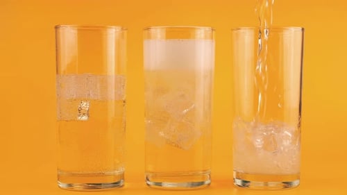 Sparkling Drinks Poured Into Glasses with Ice Cubes