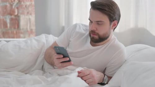 Bearded Man Using Phone While Lying in Bed