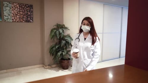 Young Woman Doctor Drinks Coffee at Desk