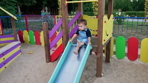 Lovely baby banging feet by the slide on the playground.
