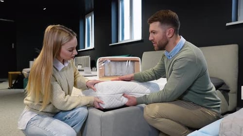 Young Couple Examining Orthopedic Mattress at Furniture Store