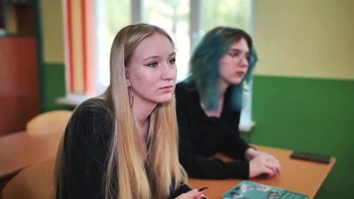 Two High School Students Paying Close Attention to Their Teacher in Class