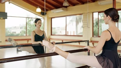 Ballet Dancer Stretching at Barre in Dance Studio