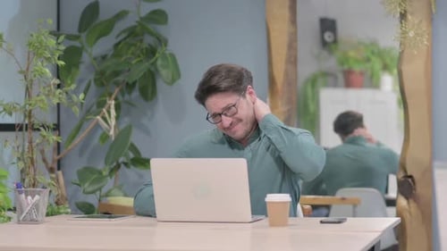Man Rubbing Neck at Desk in Office