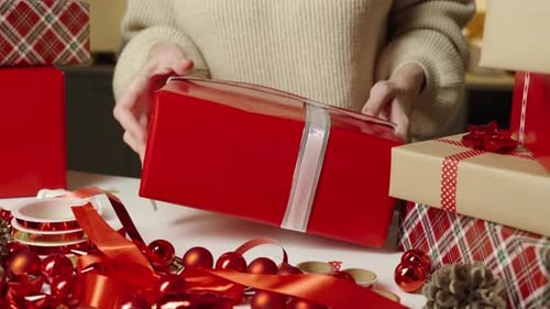 Wrapping Christmas Present with Red Ribbon at Home