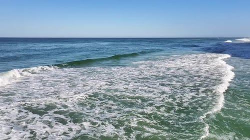 Drone over beautiful blue ocean waves with no land in sight on a clear blue sky summer day.