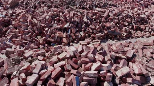 Close up aerial drone footage slowly moving over piles of red bricks.