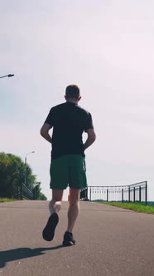 Man Running on Asphalt Path over Bridge