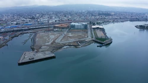 Construction along the shoreline in the bay near the shipping lanes and the cloudy city.