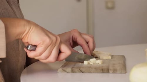 Woman Dicing Parsnip on Cutting Board in Kitchen