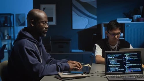 Millennial Programmer and Gen Z Web Engineer Working on Laptops in Dark Office