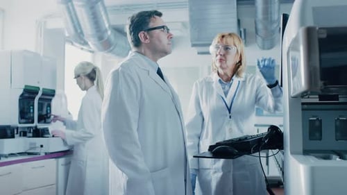 Dois pesquisadores programam equipamentos médicos com teclado de computador. Equipe de profissionais faz