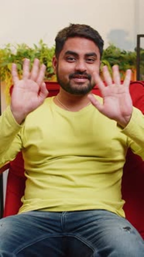 Man Sitting in Chair Waving Hello Indoors