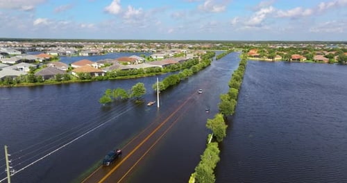 Flooded Street with Driving Vehicle and Surrounded with Water Houses in Florida Residential Area