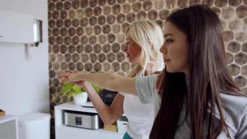 Woman Helping Other Woman Stretch Arm Indoors