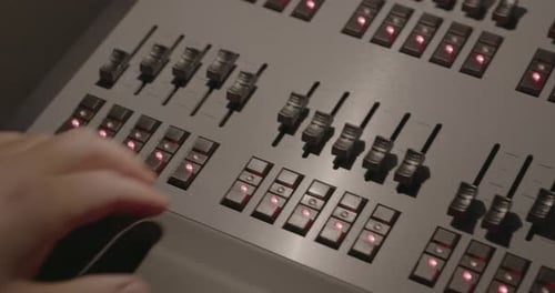 Sliding left to right close up on sliders as lighting technician's hand comes into shot and adjusts