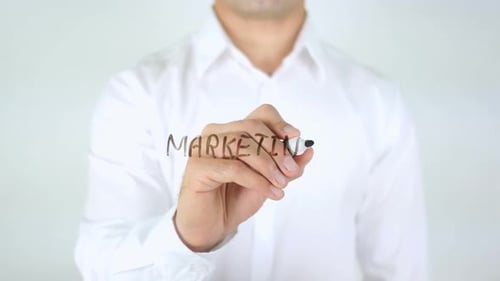 Hand Writes Word 'Marketing' on Clear Surface