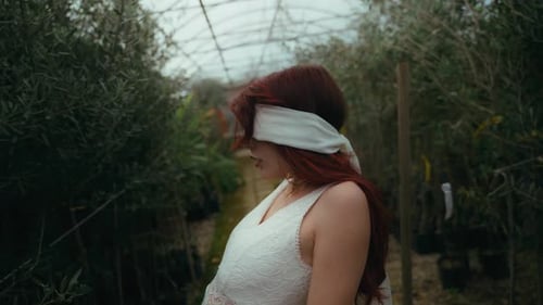 cinematic medium shot video of blindfolded young woman leaning back while letting her arms fall came