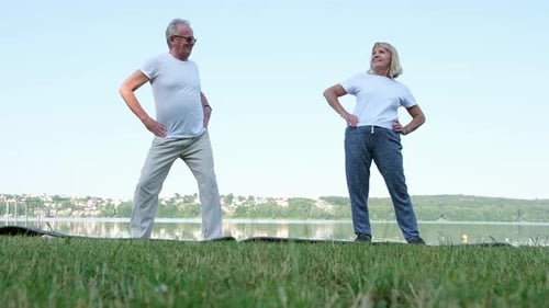 Seniors Fitness Training Standing on a Green Lawn in the Park