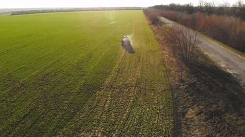 Farmer with Agricultural Machinery Fertilizing Agricultural Field in Spring Time Tractor Spreads