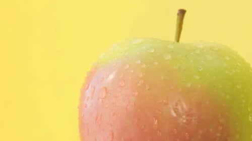 Fresh Green Apple with Water Droplets on Yellow