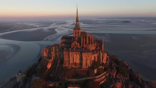 Drone flying toward and over Mont Saint-Michel at sunset, Normandy in France. Aerial forward