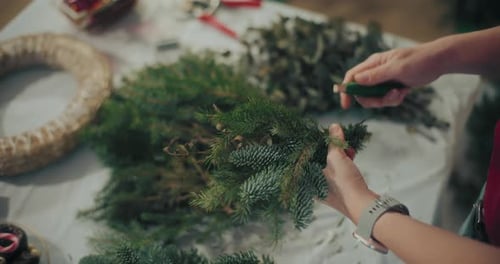 Woman Crafts Holiday Wreath with Pine Branches