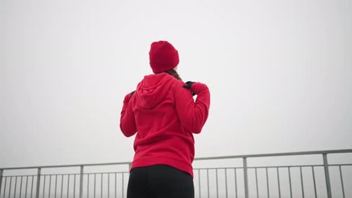 Back View of Woman Turning Arm and Head Outdoors with Foggy Atmosphere