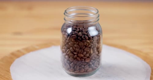 Coffee, beans and closeup on jar container for storage in cafe, kitchen or caffeine in morning