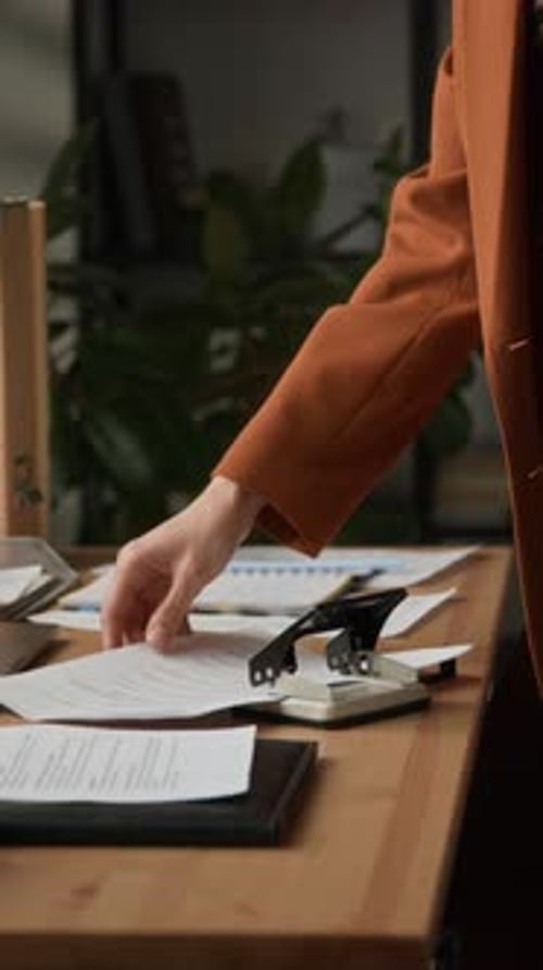 Office Worker Stapling Documents at Workplace Desk