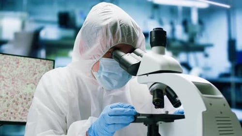 Scientist in Protective Suit Using Microscope in Laboratory