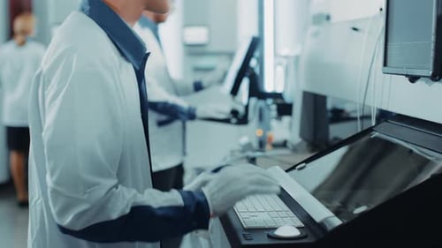 On High Tech Factory Team of Factory Engineers and Workers Use Computers for Programming Electronic