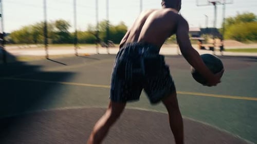 Athletic Man Dribbling Basketball on Outdoor Court