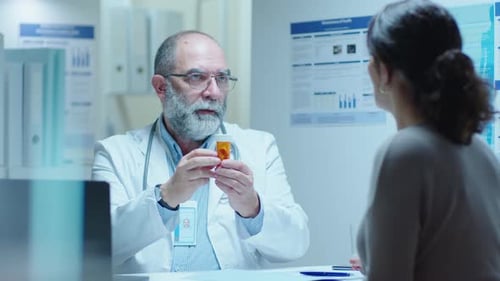 Senior Doctor Giving Pills to Female Patient in Clinic