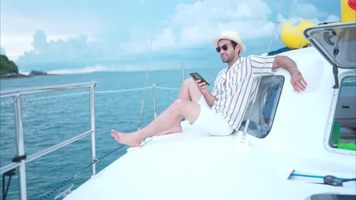Man Using Phone on Yacht Overlooking Ocean